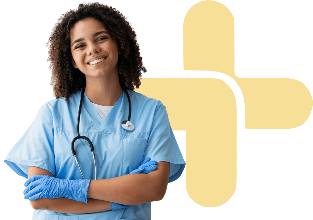 A person in blue medical scrubs, gloves, and a stethoscope stands smiling with arms crossed in front of a yellow medical cross symbol.